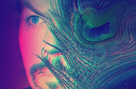 Close up image of Jack's face half obscured by a peacock feather in blue and pink tones.