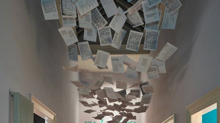 Two people looking down at an exhibit while a large exhibit of papers hangs along the ceiling above them