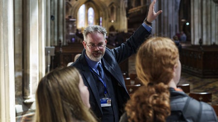 Person in a suit giving a guided tour to two people