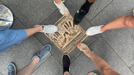 People point to the Ronnie Drew plaque with their feet on a Dublin City street