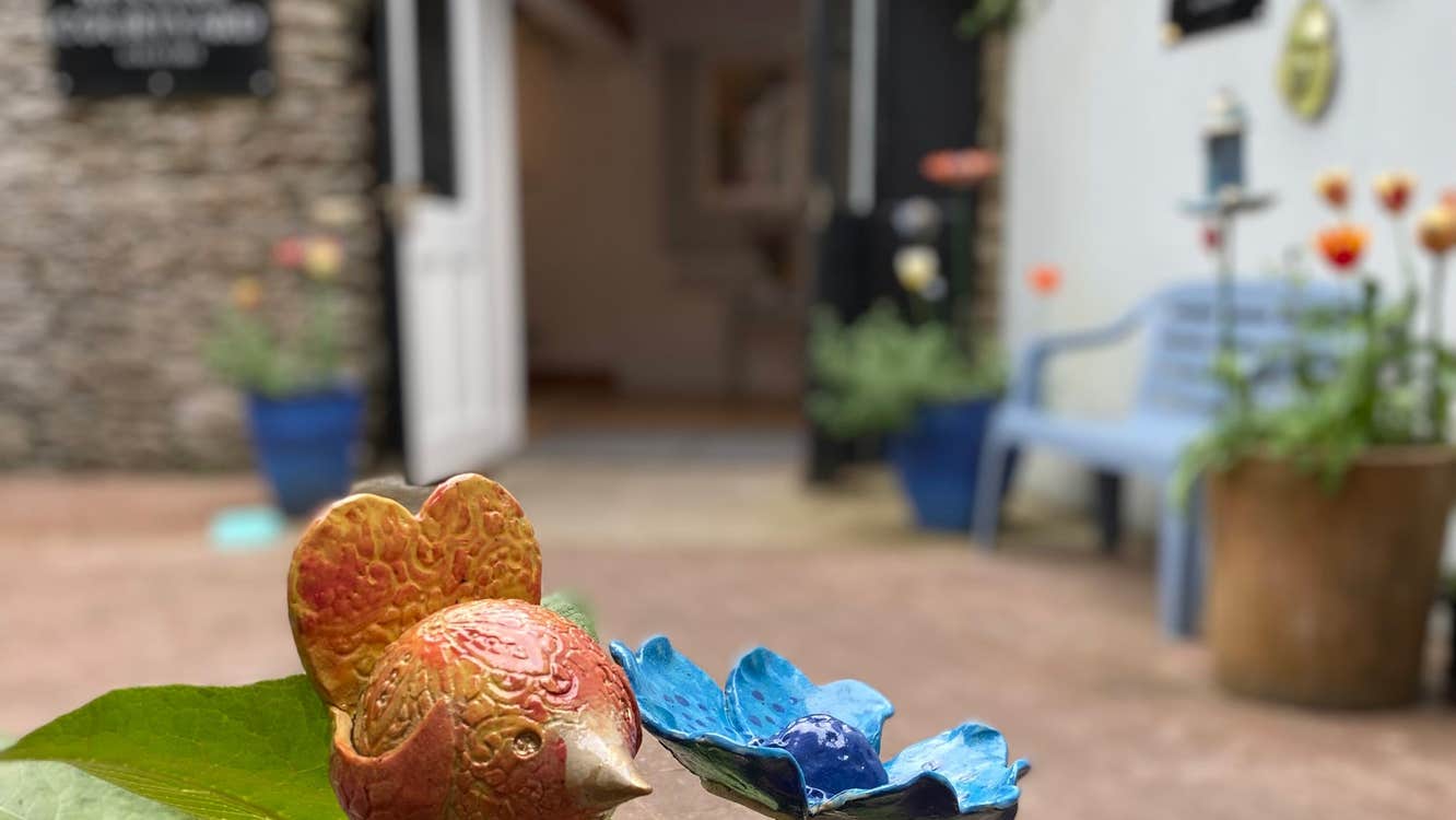 Close up of ceramic bird and flower in a courtyard