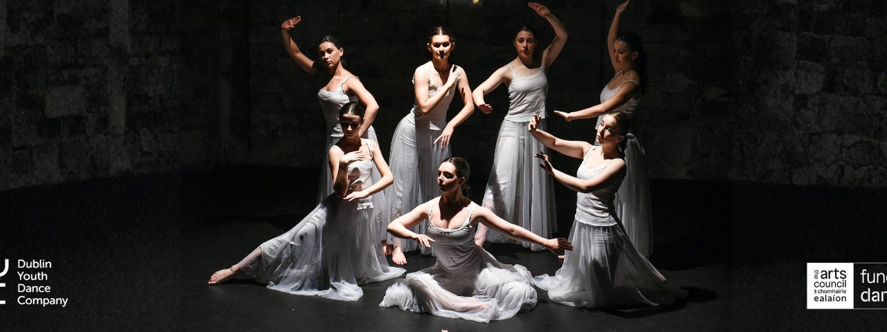 Dancers posed in a still image on a dark background