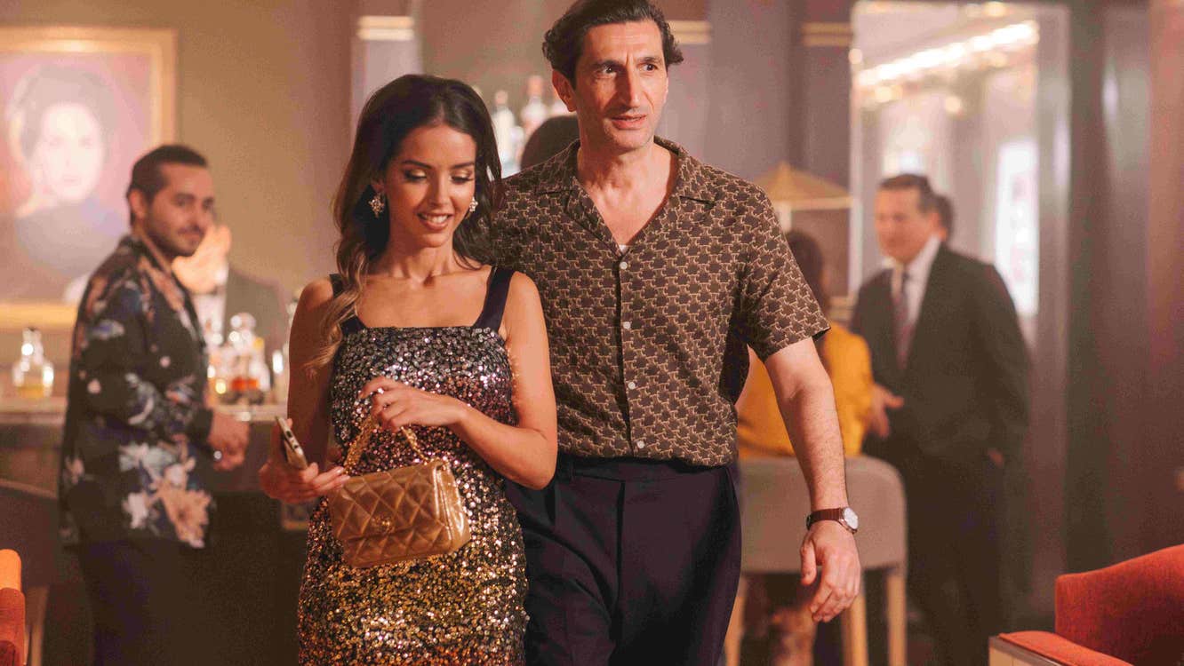 A man with his arm around a woman's waist. He seems slightly nervous.