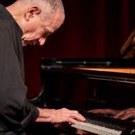 Marc Copland playing a piano.