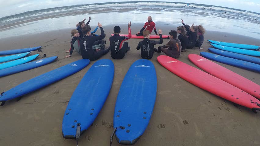A group of children enjoying a surf lesson session on the beach