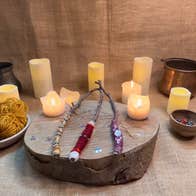 A group of lit candles around a round piece of thick wood with 3 hand made wands.