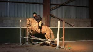 A rider and horse jumping at an indoor arena at Moorlands