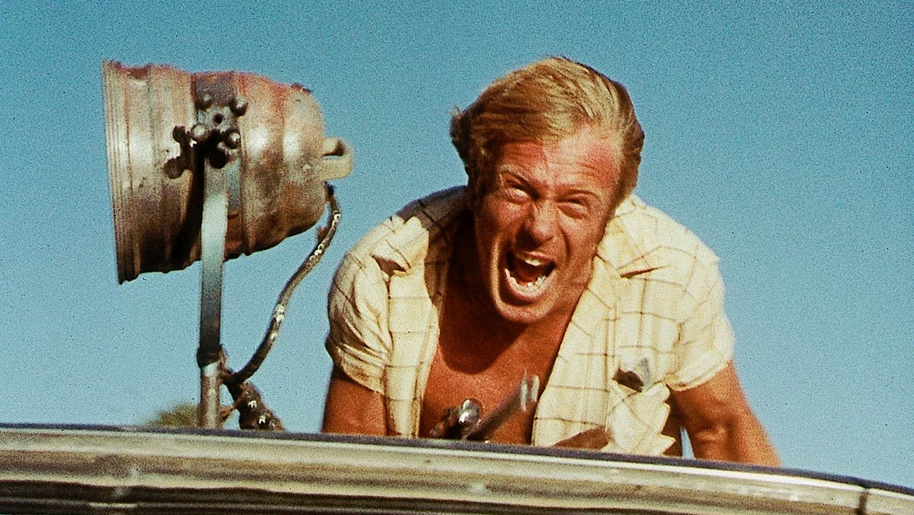 A screaming man on top of a vehicle.