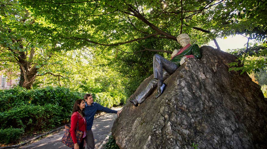 Two people looking at the Oscar Wilde statue in Merrion Square, Dublin.
