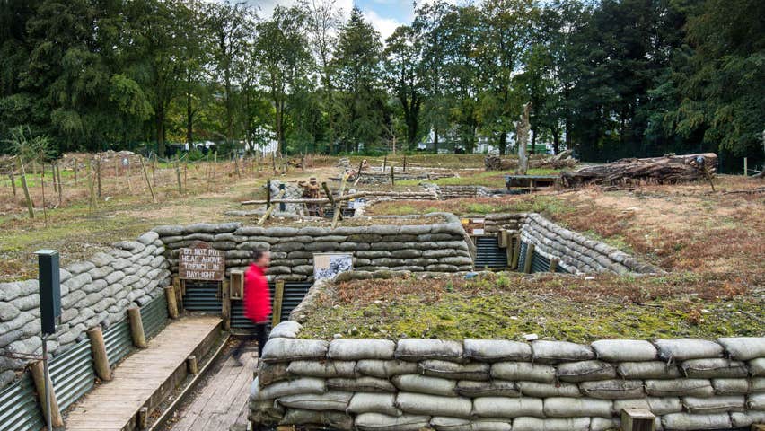 Image of large trench with sandbags either side and man with red jacket standing in it