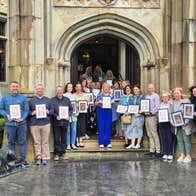 Group of people standing outside a building holding frames