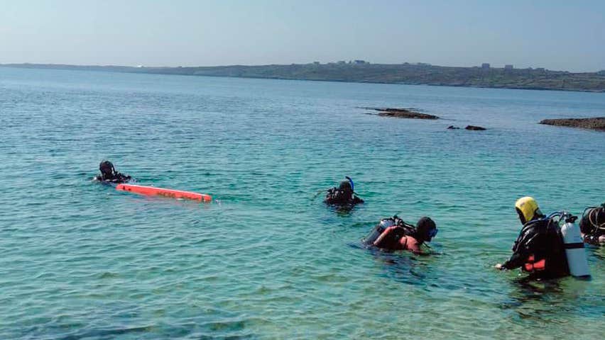 Five scuba divers in shallow sea water