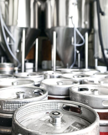 Silver kegs some with a red and a brown stripe in a brewery room