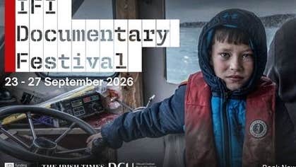 an anxious looking boy in dirty coat holding the wheel of a small boat