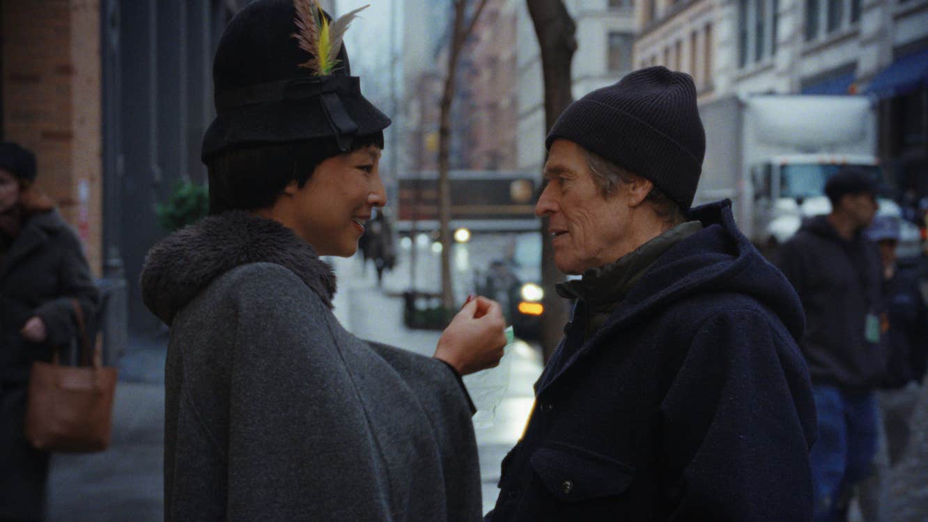 A man and a woman on a street, looking intimately into each other's eyes.