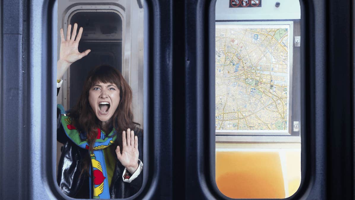 A woman is seen shouting through the window of a train with hands pressed flat against the glass