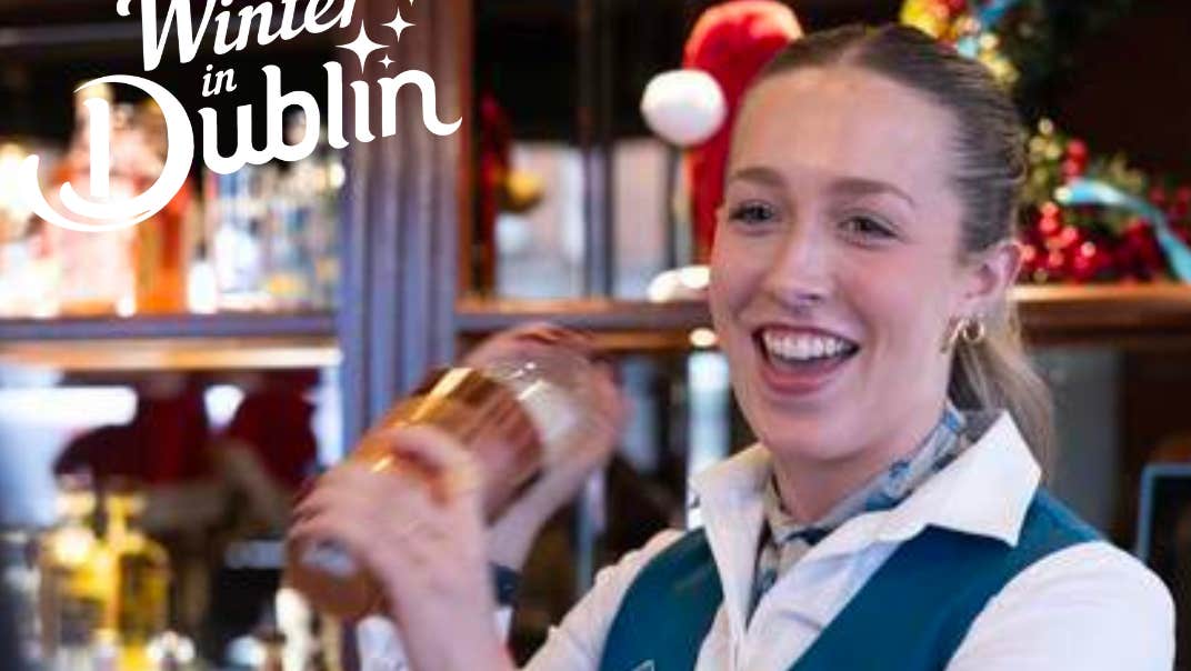 A smiling bartender is shaking a cocktail maker