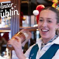 A smiling bartender is shaking a cocktail maker