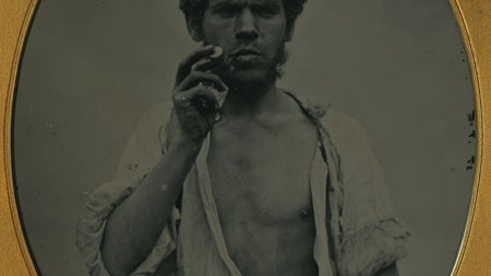 Oval shaped black and white image of a man in a gold coloured frame