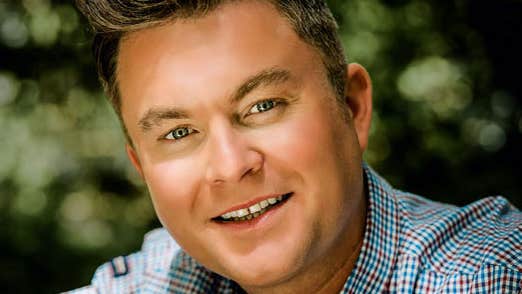 Close up of a smiling man in a small check shirt.