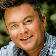 Close up of a smiling man in a small check shirt.