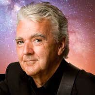 A smiling man against dark blue, purple and orange starry sky