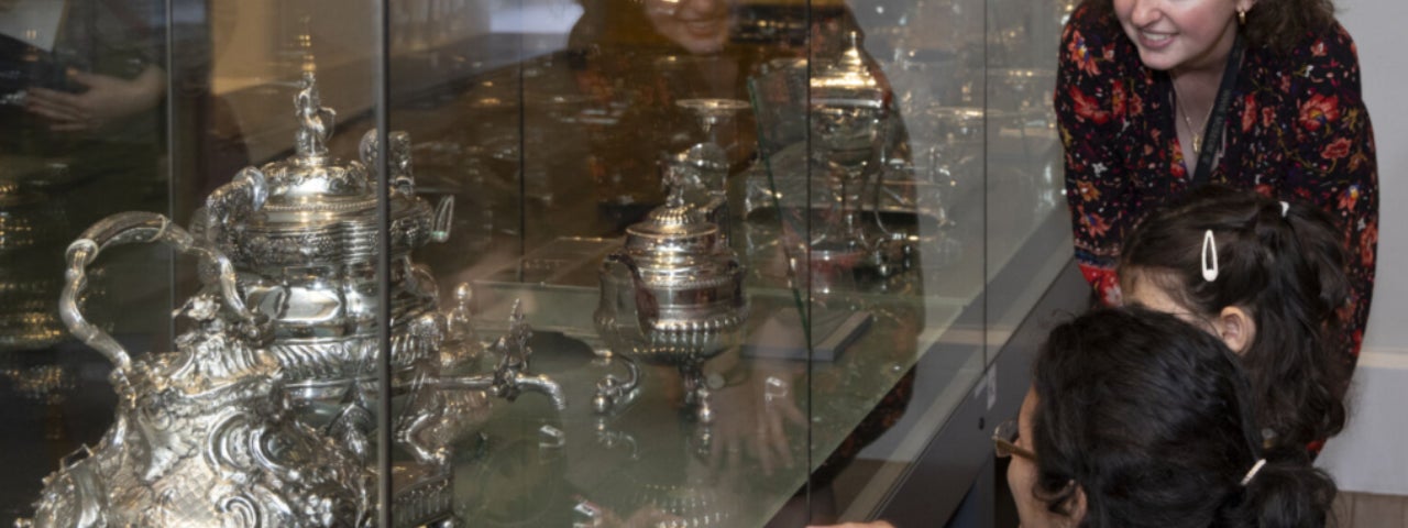 Family group and Museum Educator exploring the Irish Silver gallery