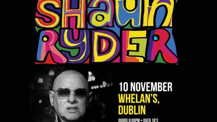 Black and white photo of man with bald head and dark glasses with large multicoloured text above