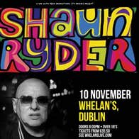 Black and white photo of man with bald head and dark glasses with large multicoloured text above