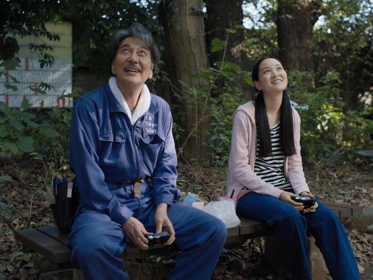An old man and a young woman are seated, happily looking at the sky.