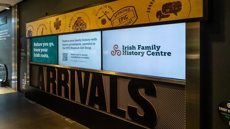 Three screens on a wall displaying information on the Irish Family History Centre