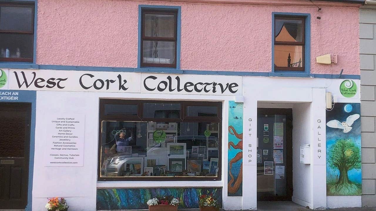 Pink and white exterior shop front of West Cork Collective with art on display in window