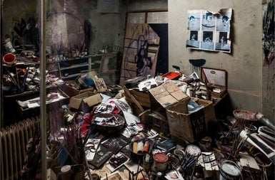 An image of a room strewn will all sorts of discarded items such as paint tins and magazines