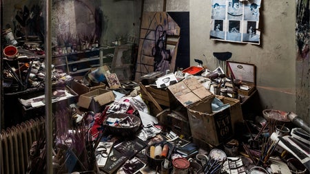 An image of a room strewn will all sorts of discarded items such as paint tins and magazines