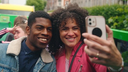 Two people sitting on an open top bus taking a selfie