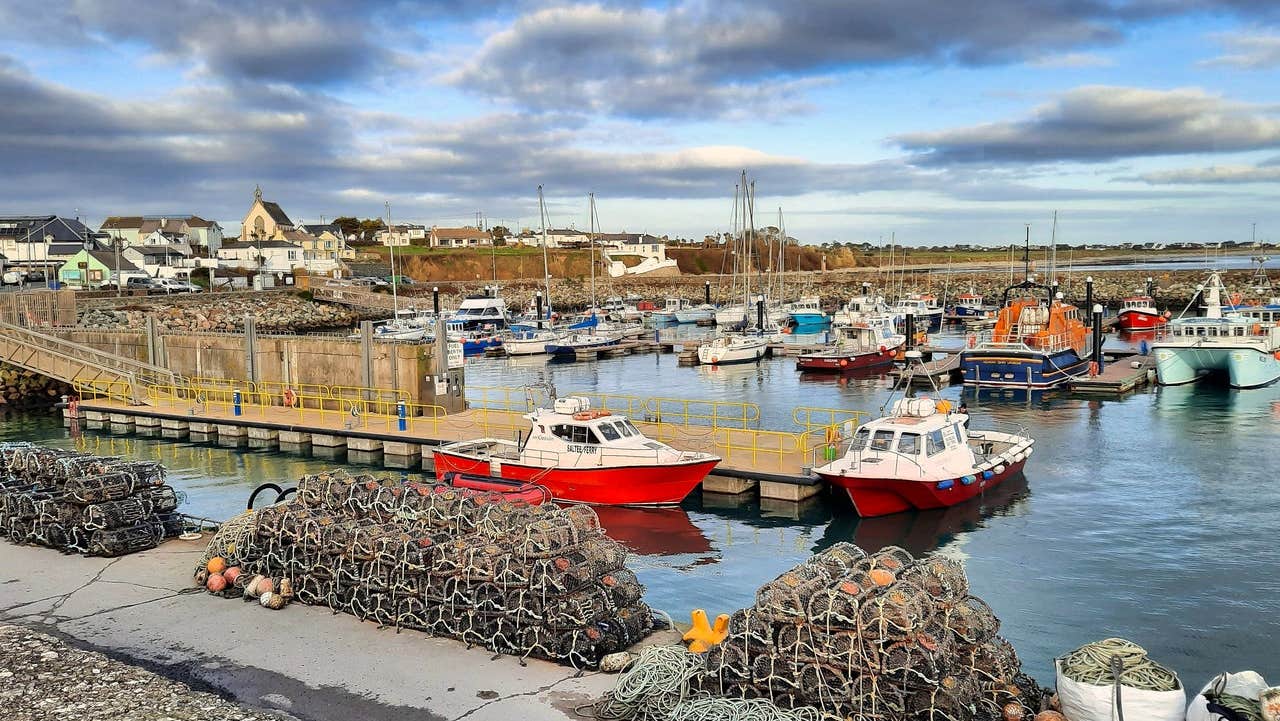 Pier to two red fishing boats with Kilmore Quay Marina in the background