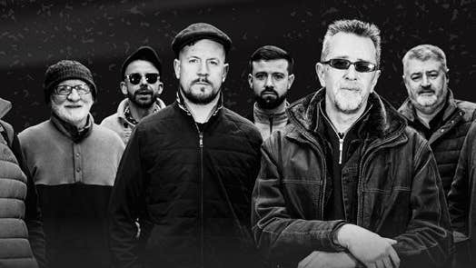 Group of 8 men in outdoor coats, some wearing sunglasses.