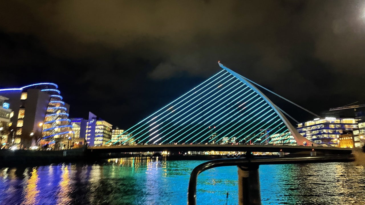The Samuel Beckett Bridge viewed from one of the boats in the middle of the River Liffey. The bridge is illuminated on blue lights as part of a display.