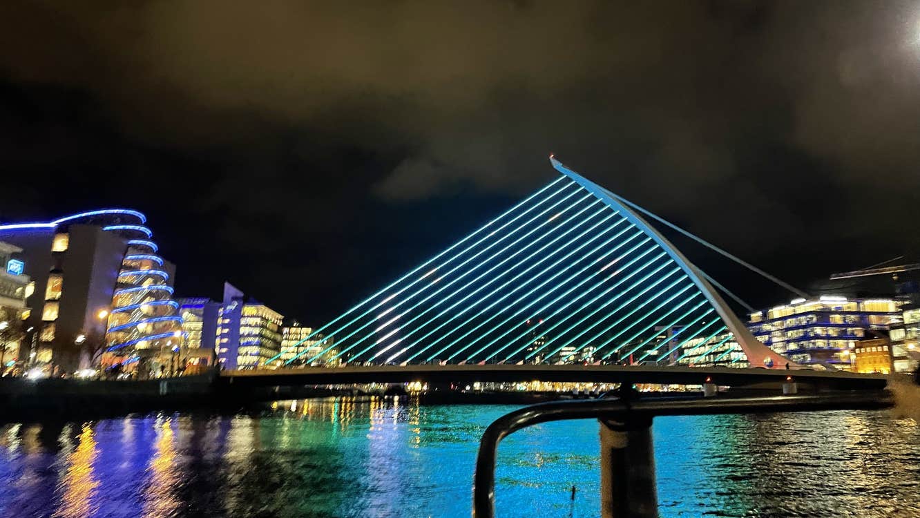 The Samuel Beckett Bridge viewed from one of the boats in the middle of the River Liffey. The bridge is illuminated on blue lights as part of a display.