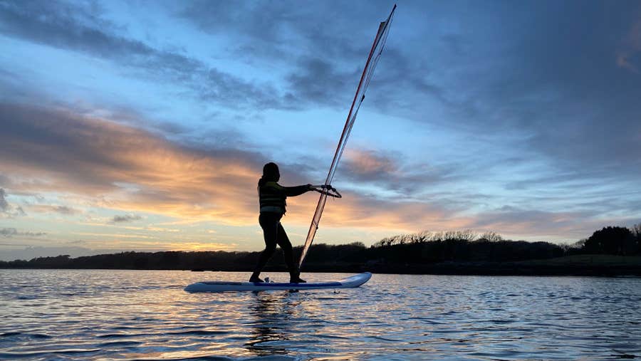 A girl windsurfing at sunset with Rusheen Bay Windsurfing