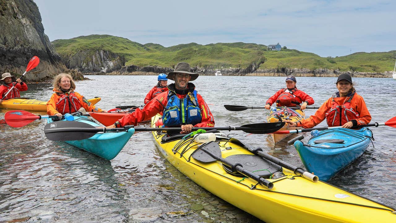 People sitting in their sea kayaks at the water's edge with H2O Sea Kayaking