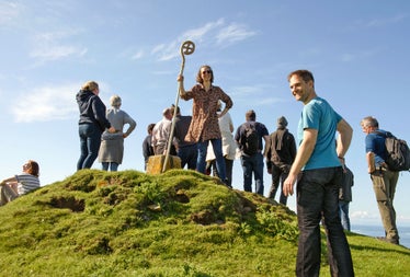 Lambay Nature Walking Tours group on a hill with one woman holding a decorated staff