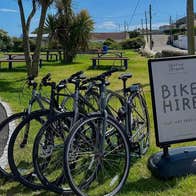 Four bikes parked in a park beside a bike hire sign