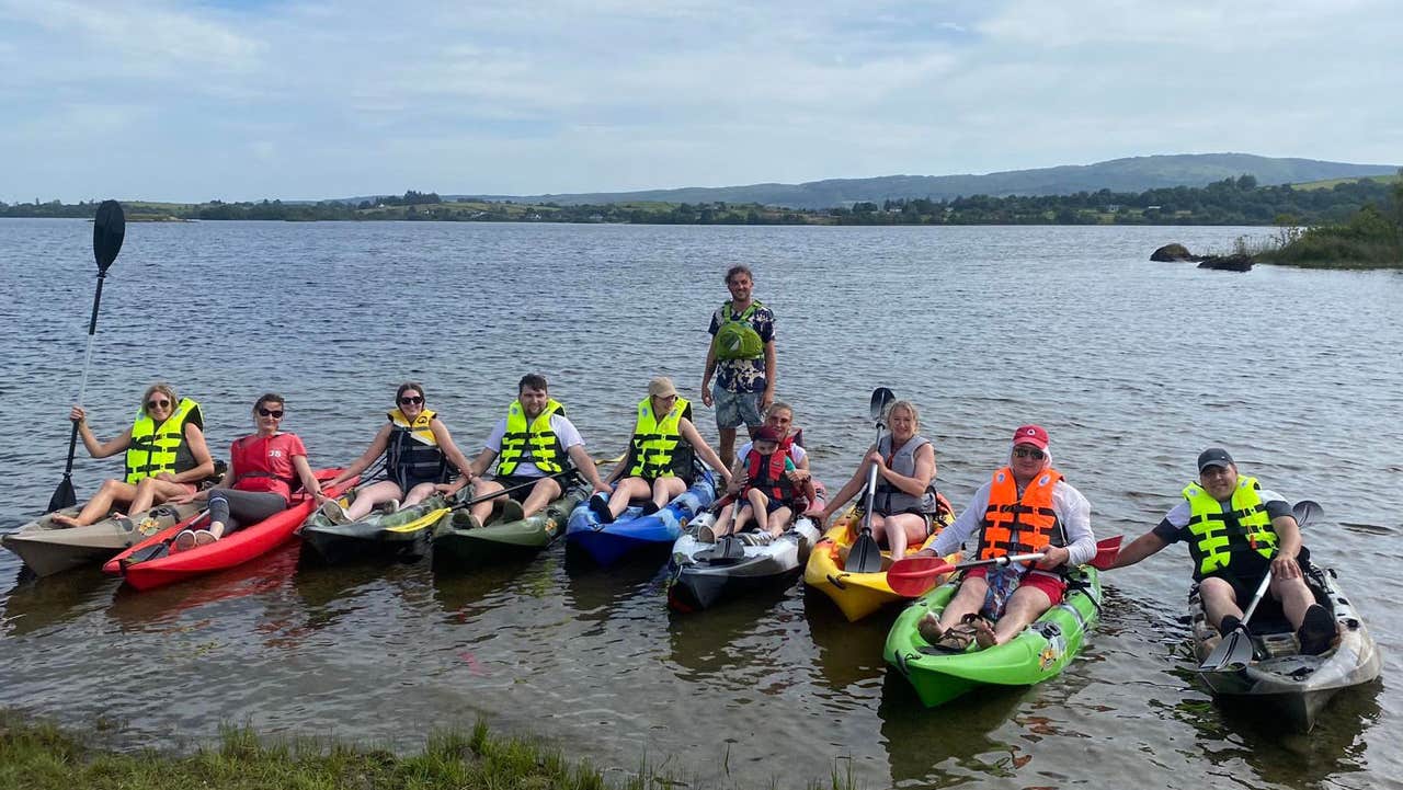 Group of people on kayaks by the lakeshore with Lough Corrib Adventures