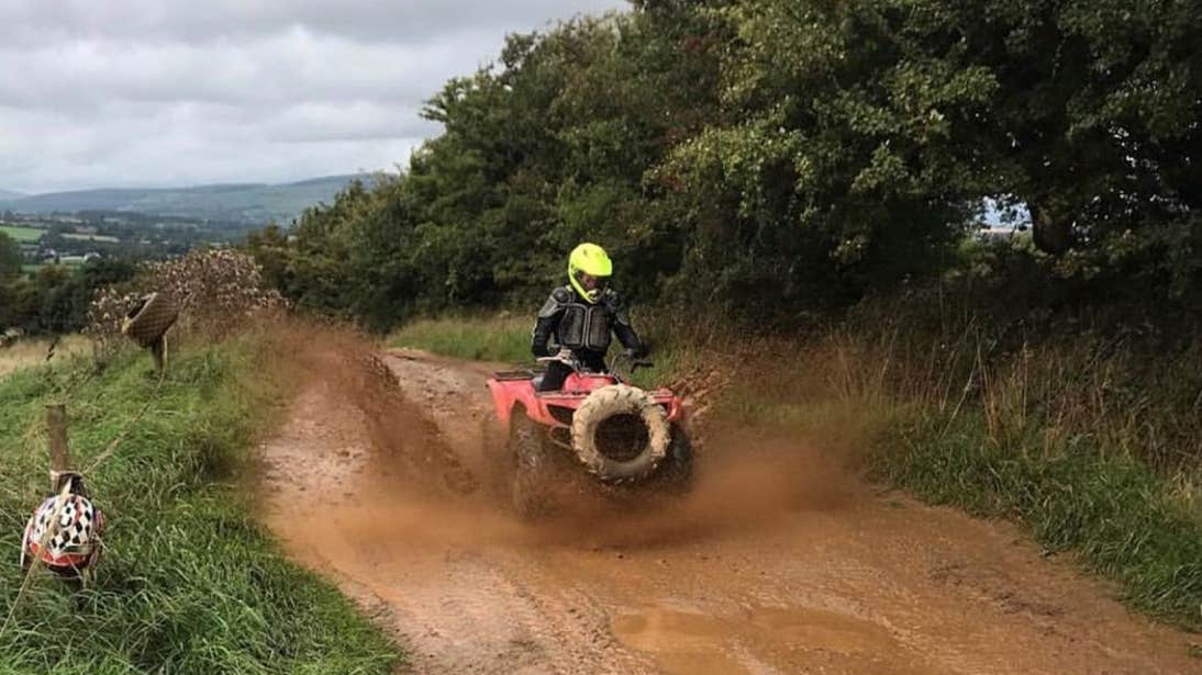 A person riding a quad through a muddy puddle with Quadventure, County Wexford