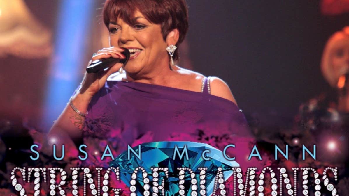 A woman singing into a microphone in a purple coloured top with text in blue and diamond shapes