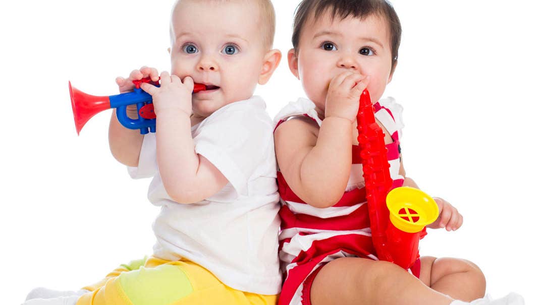 2 babies seated back to back with plastic wind instruments