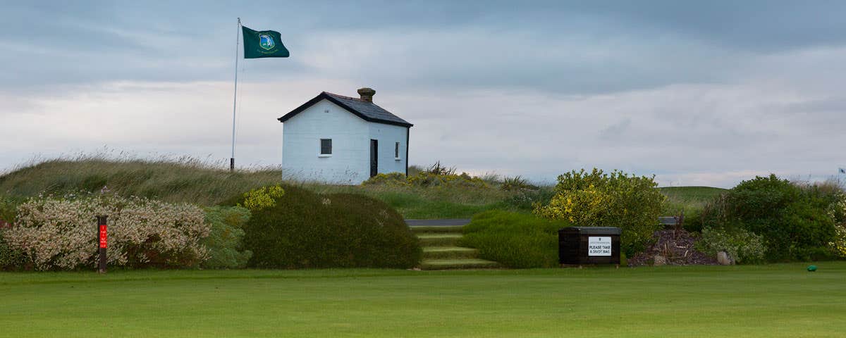 Small hut with a flag beside a golf green