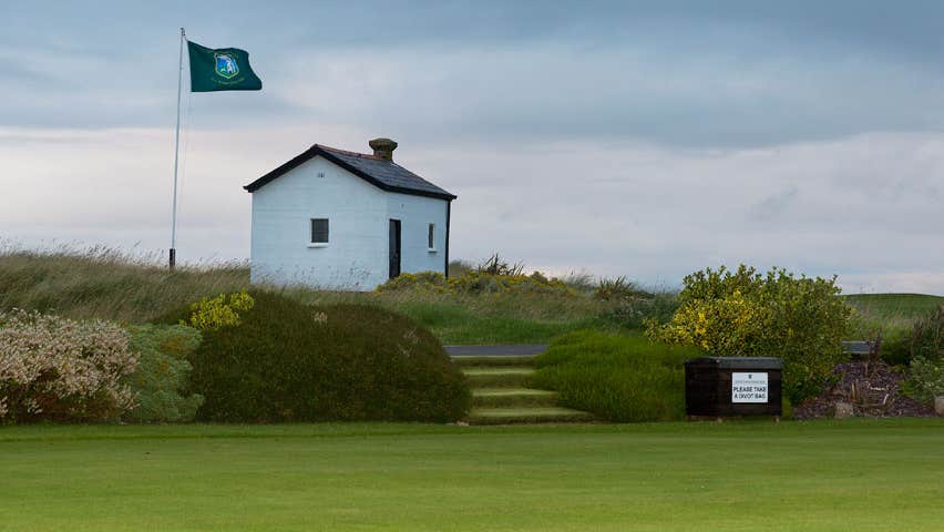 Small hut with a flag beside a golf green