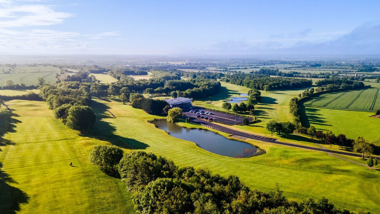 An aerial view of a golf course and lake hazard on a sunny day